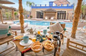 una mesa con comida y bebida frente a una piscina en La Fattoria Ecolodge, en Lalla Takerkoust