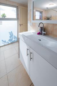 a white bathroom with a sink and a window at Appartement met prachtig uitzicht op zee! in Jan Thiel