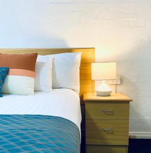 Una cama con mesita de noche con una lámpara. en Grand Country Lodge Motel, en Mittagong