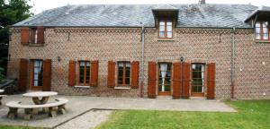 a brick building with two benches in front of it at Les mallinettes in La Neuville-aux-Joûtes