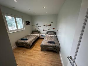2 camas individuales en una habitación con ventana en Luxury West London 3BR House, Cul De Sac, en Isleworth