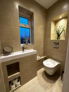 baño con aseo y lavabo y ventana en Luxury West London 3BR House, Cul De Sac, en Isleworth