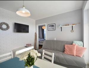 een woonkamer met een grijze bank en een tafel bij Apartamenty "u Jasia" I in Darlowko