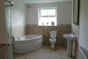 ein Badezimmer mit Badewanne, Toilette und Waschbecken in der Unterkunft Fairhead Lodge Family Friendly Holiday Home in Ballyvoy + 36 Fotos