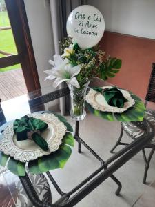 uma mesa com dois pratos e um vaso de flores em Chalé Águas Claras em Capitólio