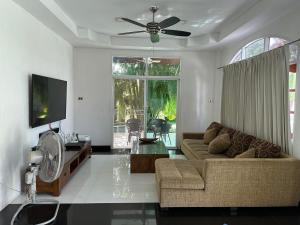 a living room with a couch and a ceiling fan at Villa Happy home in Rawai Beach