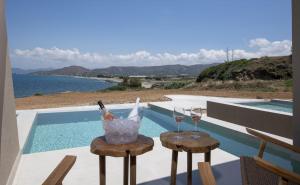 two glasses of wine sitting on stools next to a pool at Balos Beach in Kissamos