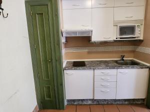 a small kitchen with white cabinets and a sink at dornajo en la plaza in Sierra Nevada