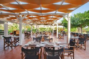 een restaurant met tafels en stoelen onder een dak bij Aeolian Village Beach Resort in Skala Eresou