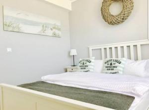 een witte slaapkamer met een bed met een krans aan de muur bij Apartamenty "u Jasia" I in Darlowko