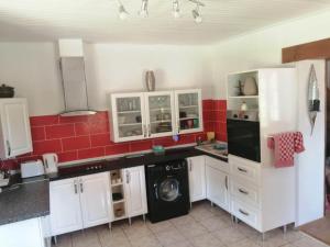 a kitchen with white cabinets and a washer and dryer at Garden Cottage in Rancon