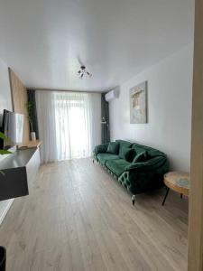 un soggiorno con divano verde in una camera di Apartament central 2 camere a Râmnicu Vâlcea