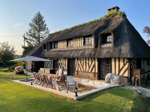 Casa con techo de paja, sillas y patio. en Maison haut de gamme proche de Deauville-Trouville en Les Authieux-sur-Calonne