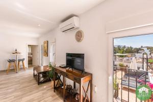 ein Wohnzimmer mit einem TV und einem Balkon in der Unterkunft Town house with roof terrace in heart of Vinuela in Viñuela