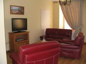 ein Wohnzimmer mit roten Ledermöbeln und einem Flachbild-TV in der Unterkunft Le presbytere in Douzy
