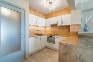 eine Küche mit weißen Schränken und einer blauen Tür in der Unterkunft Ster der Zee - zeedijk app voor 6pers met zeezicht in Middelkerke + 13 Fotos
