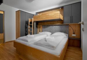 a bedroom with a bunk bed with white sheets at Zapfig Living Arlberg in Wald am Arlberg