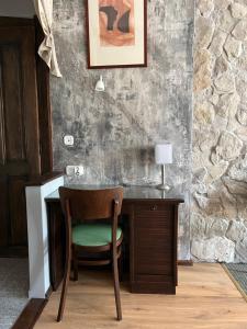uma secretária com uma cadeira ao lado de uma parede de pedra em Villa Sagan em Zamárdi
