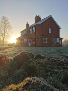 a large brick house with the sun setting behind it at Bainvalley Cottages peaceful South Cottage in Lincolnshire