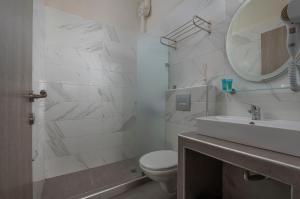 a bathroom with a toilet and a sink and a mirror at Sunshine Apartments in Neos Marmaras +36 photos