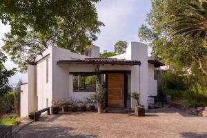a white house with a wooden door and trees at Valle de Bravo Casa Santa Rosa in Valle de Bravo