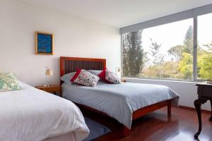 a bedroom with two beds and a large window at Valle de Bravo Casa Santa Rosa in Valle de Bravo