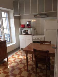 kuchnia ze stołem, kuchenką mikrofalową i lodówką w obiekcie Le capucin w mieście Mont-Dore