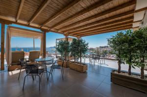 a patio with tables and chairs and a view of the ocean at Sunshine Apartments in Neos Marmaras