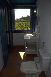 a bathroom with a toilet and a sink and a window at FAZENDAS ANTIGAS HOTEL in Sumidouro