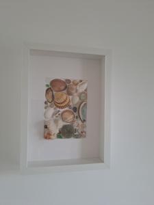 a framed picture of shells in a white frame at Kuća za odmor "Plaža" in Tkon