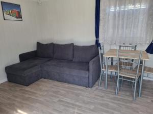 a living room with a couch and a table at 365PAM - Domek Letniskowy Kolory Lata - Z KLIMATYZACJĄ I PARKINGIEM in Sarbinowo +12 photos