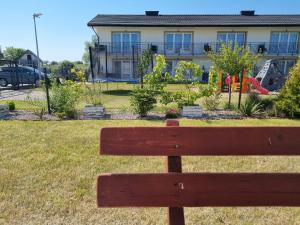 a wooden bench sitting in front of a house at 365PAM - Domek Letniskowy Kolory Lata - Z KLIMATYZACJĄ I PARKINGIEM in Sarbinowo