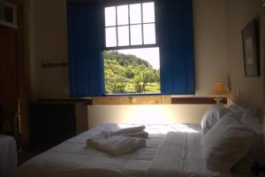 a bedroom with a bed with a window at FAZENDAS ANTIGAS HOTEL in Sumidouro