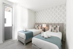 una habitación de hotel con 2 camas y una silla en Casalinga en Nazaré