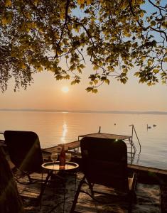 a table and chairs sitting next to a lake at TóPartiHáz in Balatonszárszó