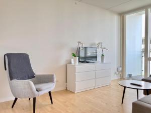 Una sala de estar con una silla y un televisor. en Newly Built 1 Bedroom Apartment With Balcony, en Aarhus