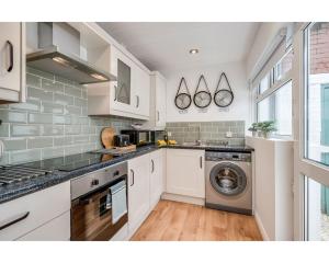 een keuken met witte kasten en een wasmachine en droger bij Central Belfast Apartments BELFAST WORK-REST-PLAY R&R in Belfast