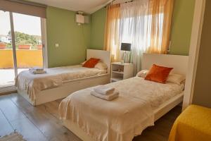 OlivellaにあるAmazing Vila close to Sitges, jacuzzi, swimming pool & exellent viewsの緑の壁と窓が特徴の客室で、ベッド2台が備わります。