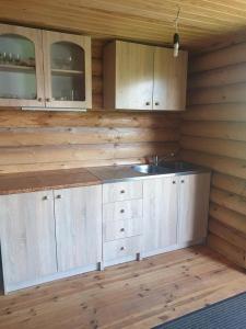 a kitchen with wooden walls and a sink and cabinets at Karostas pirts namiņš in Liepāja