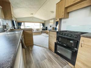 a kitchen with a stove and wooden cabinets at Lovely 8 Berth Caravan At Manor Park Nearby Hunstanton Beach 23107s in Hunstanton