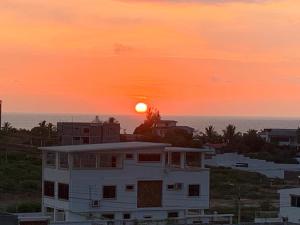 un coucher de soleil sur une maison blanche avec l'océan en arrière-plan dans l'établissement Punta Blanca 5.5, Dpto Vista al mar, à Punta Blanca