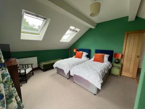 two beds in a room with green walls and windows at 2 Guests Studio - Free Parking - Stunning Views in Bruton
