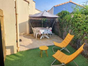 une terrasse avec une table, des chaises et un parasol dans l'établissement Maisonnette Les Sables, à Les Sables-dʼOlonne