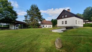 a house on a grassy field in front of a house at Hradiste Cottage in Nová Bystřice