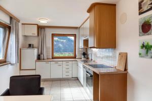 a kitchen with white cabinets and a window at Apart Spieljoch 90m2 in Bruck am Ziller