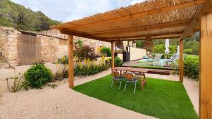 pérgola de madera con mesa y sillas sobre hierba en Can Pep de San Plana en San Jose de sa Talaia