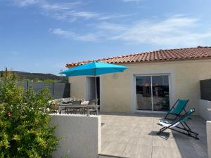 un patio con un ombrellone blu e due sedie di Val des Bruyères - gîte 15mn Pézenas avec terrasse et cour close - Parking privatif securisé - Wifi gratuit a Néffiès