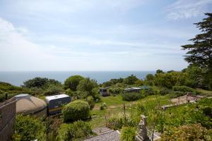 a garden with a camper and the ocean in the background at Puckaster Cove Garden Yurt in Niton