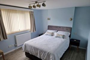 um quarto azul com uma cama com lençóis brancos e almofadas em Unique 2BD Apartment Folkestone Harbour em Kent