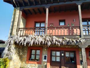a red house with a balcony with dry grass at El Pedrueco turismo rural in Nava
